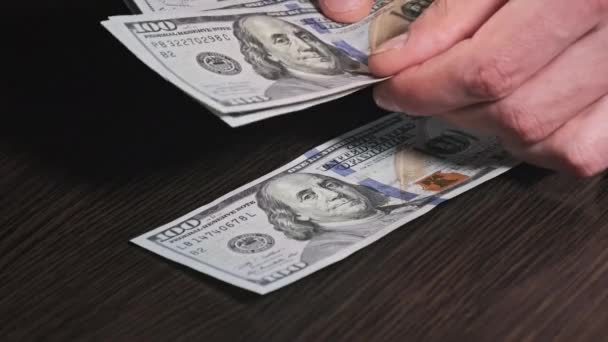在一张黑色的木制桌子上数新的100美元钞票 男人的手在数纸钱 家里的钱关门的手计数100美元的钞票 经济概念 — 图库视频影像