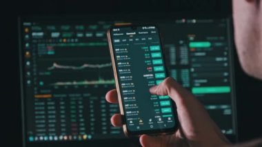 Investor checking cryptocurrency price on smartphone screen. Many crypto assets show growth. Green portfolio. Stock charts of the exchange rate. Businessman analyzing digital stock market investments