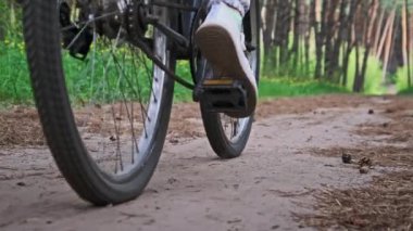 Kırsal bir parkta yeşil ağaçlar arasında bisiklet süren bir kadın. Bisikletli genç bir kadın yaz günü yol boyunca ağır çekimde bisiklet sürüyor. Spor yaşam tarzı, boş zaman aktivitesi, tatil