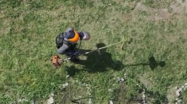Adam yavaş çekimde çimleri manuel benzin çim biçme makinesiyle biçiyor. Çim biçme makinesiyle çim biçme işlemi. Kamu çalışanının en üst manzarası yeşil çimleri biçiyor. Bahçe bakımı aletleri. Yaz.