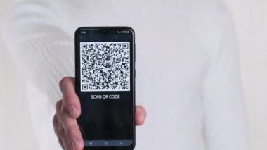 Erkek el, beyaz arka planda akıllı telefondaki QR kodunu gösteriyor. Cep telefonu ekranındaki yazı - QR kodunu tara. İzole edilmiş. Dijital para kavramı, güvenli, ilaç, covid, ödeme, dijitalleştirme