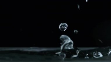 Yavaş çekimde suyun yüzeyine çok su damlası düşer, makro çekim. Damlalar sıvı yüzeyi vurarak dalgalar, daireler ve sıvı türbülans oluşturur. Yüzey gerilimi. 240 fps.