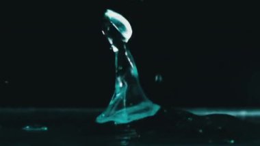 Yavaş çekimde suyun yüzeyine çok su damlası düşer, makro çekim. Damlalar sıvı yüzeyi vurarak dalgalar, daireler ve sıvı türbülans oluşturur. Yüzey gerilimi. 240 fps.