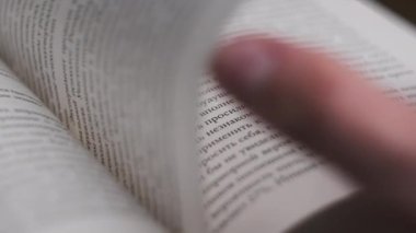 Kitap çevirme sayfaları, yakın çekim, yavaş çekim. Erkek eli bir kitabın sayfalarını karıştırır, seçici odaklanma. Kalın bir kitabın sayfalarını hızlıca çeviriyorum. Ayrıntılı görüş. Okuma, öğrenme, kendini eğitme.
