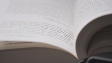Kitap çevirme sayfaları, yakın çekim, yavaş çekim. Erkek eli bir kitabın sayfalarını karıştırır, seçici odaklanma. Kalın bir kitabın sayfalarını hızlıca çeviriyorum. Ayrıntılı görüş. Okuma, öğrenme, kendini eğitme.