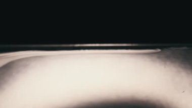 Su damlası su yüzeyine yavaş çekimde düşer, süper makro çekim. Su yüzeyine çarptıktan sonra farklı daireler oluşur. Sıvının yüzey geriliminin etkisi. 240 fps.