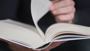 Genç adam kitap okuyor ve sayfaları çeviriyor, kapat, yavaş çekim. Erkek eller bir kitap tutuyor ve sayfaları çeviriyor. Tanımlanamayan bulanık bir adam metni inceliyor. Öğrenme, kendini eğitme. 4K