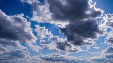 Katmanlı bulutların zaman akışı parlak güneşin altında mavi gökyüzünde ilerler. Cirrus bulutları şekil değiştirir ve bulut uzayında çözünür. Görkemli pofuduk gökyüzü. Bulutlu zaman çizelgesi. Hava değişimi. İnanılmaz doğa 4K