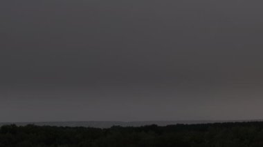 Fırtına bulutlarında şimşek çakıyor. Şiddetli bulutlar birden fazla şimşek ve fırtına patlaması getirir. Orman ufkunun üzerinde akşam vakti büyük yıldırımlar düşüyor. Ağır çekim. 4K