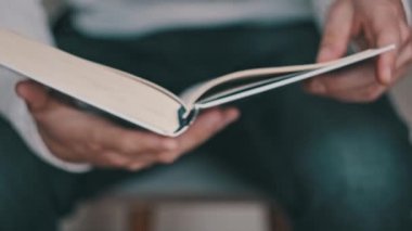 Genç adam kitap okuyor ve sayfaları çeviriyor, kapat, yavaş çekim. Erkek eller bir kitap tutuyor ve sayfaları çeviriyor. Tanımlanamayan bulanık bir adam metni inceliyor. Öğrenme, kendini eğitme. 4K