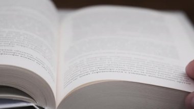 Kitap çevirme sayfaları, yakın çekim, yavaş çekim. Erkek eli bir kitabın sayfalarını karıştırır, seçici odaklanma. Kalın bir kitabın sayfalarını hızlıca çeviriyorum. Ayrıntılı görüş. Okuma, öğrenme, kendini eğitme.