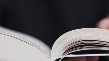 Genç adam kitap okuyor ve sayfaları çeviriyor, kapat, yavaş çekim. Erkek eller bir kitap tutuyor ve sayfaları çeviriyor. Tanımlanamayan bulanık bir adam metni inceliyor. Öğrenme, kendini eğitme. 4K