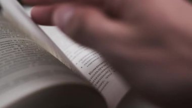 Kitap çevirme sayfaları, yakın çekim, yavaş çekim. Erkek eli bir kitabın sayfalarını karıştırır, seçici odaklanma. Kalın bir kitabın sayfalarını hızlıca çeviriyorum. Ayrıntılı görüş. Okuma, öğrenme, kendini eğitme.