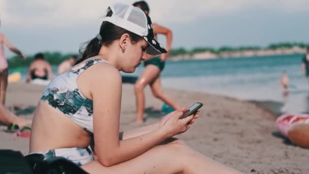 Beautiful Girl Bathing Suit Sits Sandy Beach Phone Her Hands — Stock Video