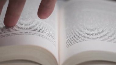 Kitap çevirme sayfaları, yakın çekim, yavaş çekim. Erkek eli bir kitabın sayfalarını karıştırır, seçici odaklanma. Kalın bir kitabın sayfalarını hızlıca çeviriyorum. Ayrıntılı görüş. Okuma, öğrenme, kendini eğitme.