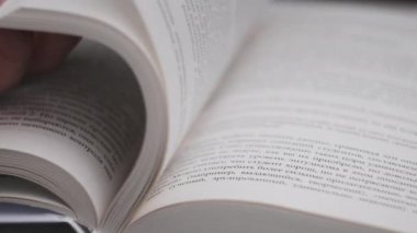 Kitap çevirme sayfaları, yakın çekim, yavaş çekim. Erkek eli bir kitabın sayfalarını karıştırır, seçici odaklanma. Kalın bir kitabın sayfalarını hızlıca çeviriyorum. Ayrıntılı görüş. Okuma, öğrenme, kendini eğitme.