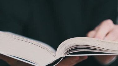 Kitap okumak ve sayfaları çevirmek, kapat. Genç adam bir kitap tutuyor ve sayfaları çeviriyor, ağır çekimde. Tanımlanamayan bir adam kitap okuyor ve sayfaları karıştırıyor. Kendi kendini eğitme