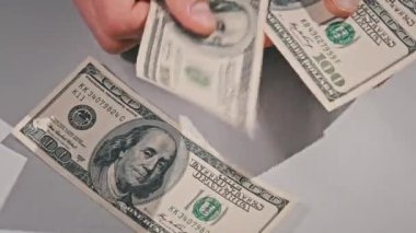 Counting old hundred dollar banknotes on a white table. Male hands counting paper money, home cash. Close-up of a hand counting 100 USD bills. Business, finance, economy concept.