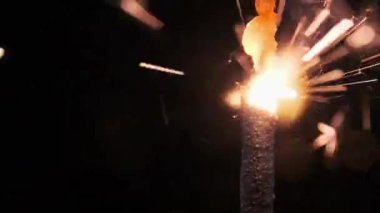 Ağır çekimde siyah arka planda maytap, makro çekim. Aydınlık maytap konsepti. Bengal ışığı karanlıkta yanıyor. Havai fişek fişeklerinin yakın çekimi. Barut kıvılcımları atar.