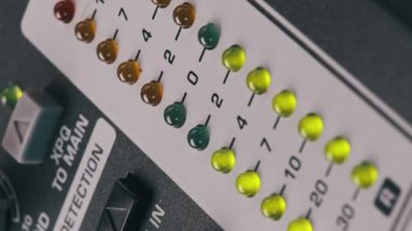 Vertical video LED indicator of sound level signal on mixing console. LED strip in green and yellow on output level indicator. Volume level changes of indicator lights. VU meters on sound desk. Macro