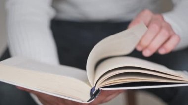 Kitap okumak ve sayfaları çevirmek, kapat. Genç adam bir kitap tutuyor ve sayfaları çeviriyor, ağır çekimde. Tanımlanamayan bir adam kitap okuyor ve sayfaları karıştırıyor. Kendi kendini eğitme