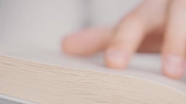Genç adam kitap okuyor ve sayfaları çeviriyor, kapat, yavaş çekim. Erkek el bir kitabı tutar ve öğrenirken parmaklarını sayfa boyunca hareket ettirir. Adam sayfaları karıştırıyor. Metin okumak, öz eğitim