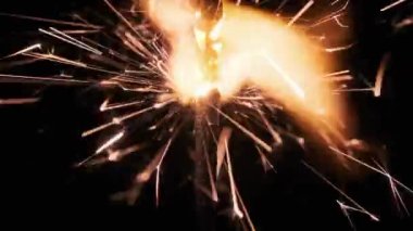 Lightening sparkler on black background in slow motion, macro shot. Sparks from gunpowder scatter. Firework sparkler burning isolated in dark. Holiday, Newyear concept. Close-up firework sparkler burn