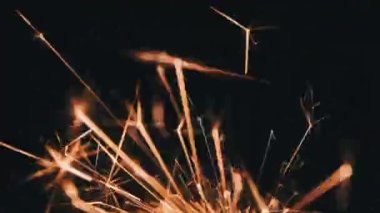 Ağır çekimde siyah arka planda maytap, makro çekim. Aydınlık maytap konsepti. Bengal ışığı karanlıkta yanıyor. Havai fişek fişeklerinin yakın çekimi. Barut kıvılcımları atar.