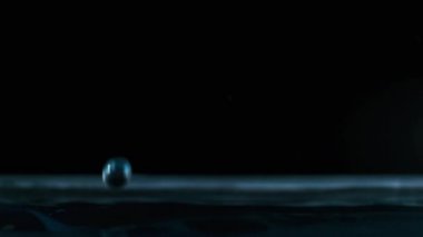 Yavaş çekimde suyun yüzeyine çok su damlası düşer, makro çekim. Damlalar sıvı yüzeyi vurarak dalgalar, daireler ve sıvı türbülans oluşturur. Yüzey gerilimi. 240 fps.