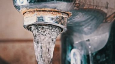 Water flows through the aerator from an old contaminated tap with calcium and grime into a sink. Faucet with running jet of water in Slow Motion, macro shot. Water turns on and then off. Close-up.