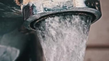 Su eski kirlenmiş bir musluktan kalsiyum ve kir dolu bir lavaboya akıyor. Ağır çekimde çalışan su dolu musluk, makro çekim. Su açılıp kapanıyor. Yakın plan..