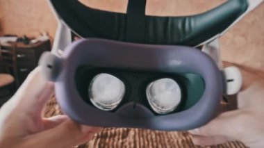 Point of view man taking on VR helmet at bedroom. POV of putting on VR glasses virtual reality at home. Young male hands hold virtual reality helmet indoors. Immersion in the meta-universe, Metaverse