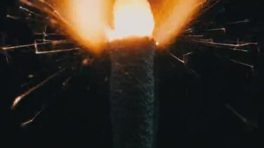 Ağır çekimde siyah arka planda maytap, makro çekim. Aydınlık maytap konsepti. Bengal ışığı karanlıkta yanıyor. Havai fişek fişeklerinin yakın çekimi. Barut kıvılcımları atar.