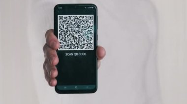Erkek el, beyaz arka planda akıllı telefondaki QR kodunu gösteriyor. Cep telefonu ekranındaki yazı - QR kodunu tara. İzole edilmiş. Dijital para kavramı, güvenli, ilaç, covid, ödeme, dijitalleştirme