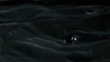Yavaş çekimde suyun yüzeyine çok su damlası düşer, makro çekim. Damlalar sıvı yüzeyi vurarak dalgalar, daireler ve sıvı türbülans oluşturur. Yüzey gerilimi. 240 fps.