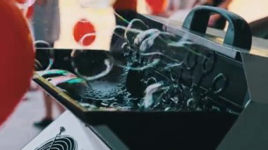 Sabun köpüğü jeneratörü açık hava festivalinde sabun köpüğü üretiyor. Çocukların tatilinde kullanılan otomatik sabun köpüğü üfleme makinesi. Yavaş çekim.