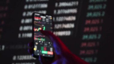 Yatırımcı, değiş tokuş sırasında akıllı telefon ekranındaki kripto para birimini kontrol ediyor. Birçok şifreli varlık fiyatları değiştirir. Döviz kurlarının borsa tabloları. İşadamı dijital borsa yatırımlarını analiz ediyor