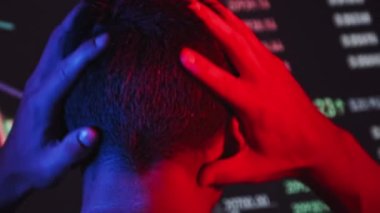 Tüccar, karanlıkta büyük bir ekrandaki kripto para çizelgelerini analiz ediyor. Kırmızı-mavi ışıklandırmalı bir adamın borsadaki döviz tablolarına bakması. Hisse senedi, bitcoin, gelecek, yatırım pazarı