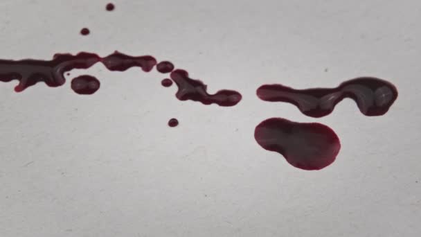 红血滴在白纸上 宏观射击 一滴一滴血被吸收到纸的纹理中 红墨水滴在纸上 戈尔在白色的表面上飞溅 血迹斑斑在白底显现出来 — 图库视频影像