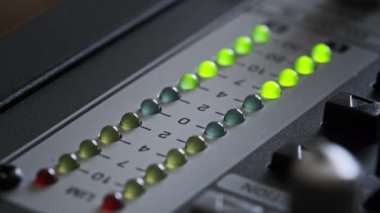 LED indicator of sound level signal on the mixing console. LED strip in green and yellow on output level indicator. Volume level changes of indicator lights. VU meters on the analog sound desk. Macro