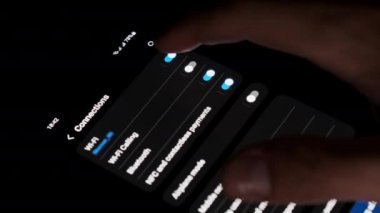 Turning off Wi-Fi on a smartphone. The wifi button is turned on the mobile phone in the connections menu. Male finger hand touching touchscreen on modern smart phone with wi fi zone on screen.