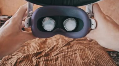 Yatak odasında sanal gerçeklik gözlüğü takmanın görüntüsü. Genç erkek eller sanal gerçeklik kaskını içeride tutuyor. Sanal gerçeklik maskesi. Yakın plan. VR kaskını evde çıkaran adamın bakış açısı.