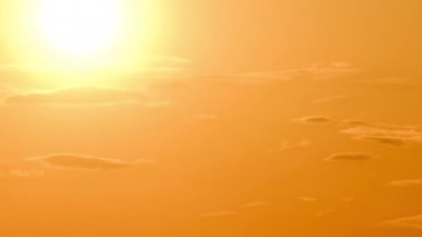 Güneş ışınlarının turuncu katmanlı bulutlar arasından gökyüzüne vurduğu dramatik bir gün batımı, Timelapse. Büyük parlak sarı güneş ufuktan aşağı doğru hareket ediyor. Zaman aşımı. Destansı bulut uzayı. İnanılmaz canlı gün batımı