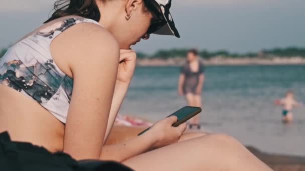 Beautiful Girl Bathing Suit Sits Sandy Beach Phone Her Hands — Stock Video