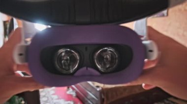 Point of view man taking on VR helmet at bedroom. POV of putting on VR glasses virtual reality at home. Young male hands hold virtual reality helmet indoors. Immersion in the meta-universe, Metaverse