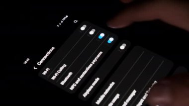 Turning on Wi-Fi on a smartphone. The wifi button is turned on the mobile phone in the connections menu. Male finger hand touching touchscreen on modern smart phone with wi fi zone on screen.