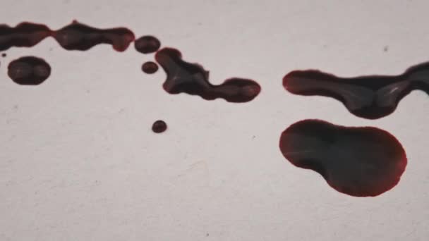 红血滴在白纸上 宏观射击 一滴一滴血被吸收到纸的纹理中 红墨水滴在纸上 戈尔在白色的表面上飞溅 血迹斑斑在白底显现出来 — 图库视频影像