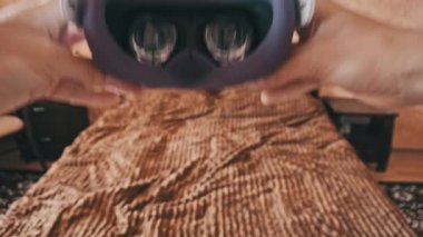 POV of putting on VR glasses virtual reality in the bedroom. Young male hands hold virtual reality helmet indoors. Virtual reality mask. Close-up. Point of view man taking of VR helmet at home.