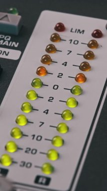 Vertical video LED indicator of sound level signal on mixing console. Close-up shot of strip in green and yellow on VU output level indicator. Volume level changes of indicator bulbs. Stereo meters