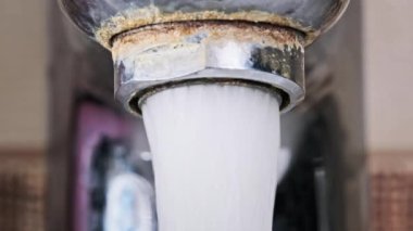 Su eski kirlenmiş bir musluktan kalsiyum ve kir dolu bir lavaboya akıyor. Ağır çekimde çalışan su dolu musluk, makro çekim. Su açılıp kapanıyor. Yakın plan..